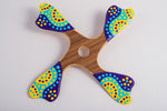 Boomerang quadripale Balabalaa en bois motifs pointillistes jaune violet et turquoise sur fond blanc