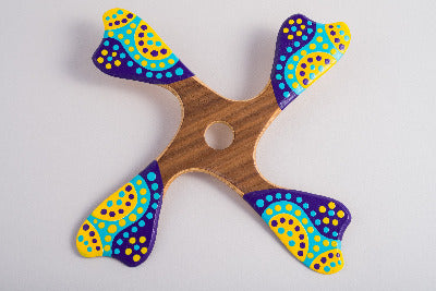 Boomerang quadripale Balabalaa en bois motifs pointillistes jaune violet et turquoise sur fond blanc