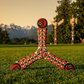 Three-blade Haida boomerang with red and black Northwest Coast Indigenous art, on a lawn with totem poles and snowy mountains