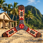 Three-blade Hawaii boomerang with Tiki tribal patterns, standing on a sandy beach with palm trees and lush tropical mountains