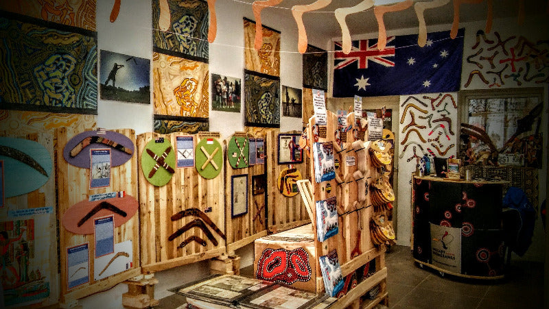 Intérieur de la boutique Wallaby Boomerangs avec présentoirs en bois, boomerangs colorés, affiches et drapeau australien 