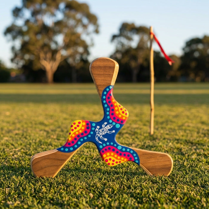 Boomerang Kadina 3 ailes avec lézard aborigène central et décoration pointilliste multicolore jaune orange rose et bleu, coucher de soleil australien