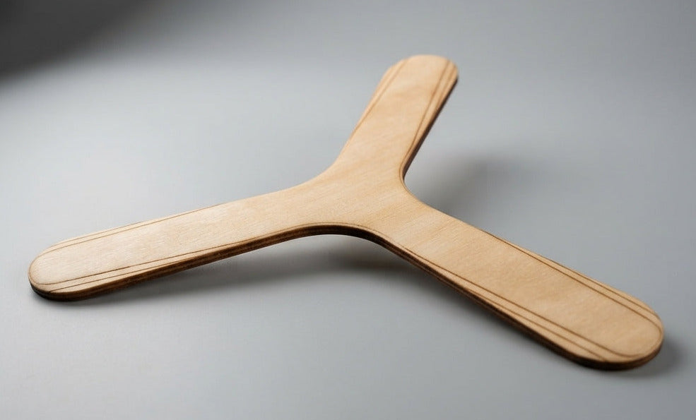 Boomerang tripale en bois de bouleau brut non peint posé sur fond gris